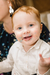 Сhild ate. The birthday boy is eating a cake. A cheerful child eats a sweet cake. A 2 year old boy celebrates his birthday in a restaurant. Happy facial expression. Closeup.