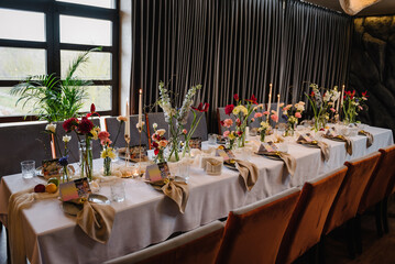 Luxury elegant table setting dinner in a restaurant. Selective focus. Preparation, decorating of banquet table for a birthday party. Wedding reception. Decor of flowers, greenery and candles. Closeup.