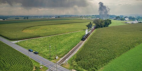 Drone View of an Antique Steam Engine Approaching Blowing Steam and Traveling Along the Countryside