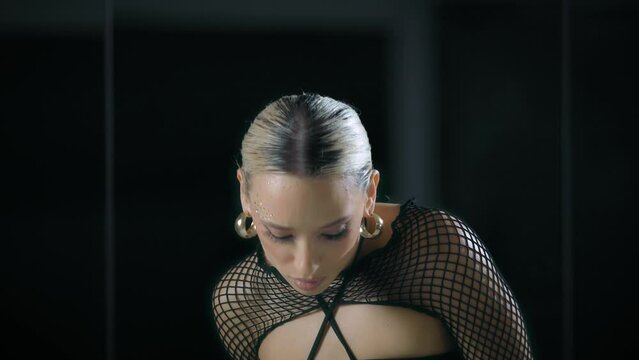 Beautiful female dancing in a mesh overlay crop top in black and baggy pants in a studio