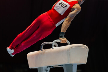 close-up gymnast performing on pommel horse competition artistic gymnastics, black background