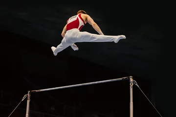Foto op Canvas gymnast performing on horizontal bar competition artistic gymnastics, black background © sports photos