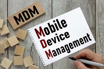 Text MDM - Mobile Device management text on torn page near wooden cubes