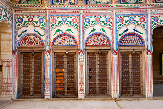 Colorful paintings and wooden windows on the outer wall of Seth Harmukhrai Sanehiram Chokhani Double Haveli, located in Mandawa, Shekhawati,  Rajasthan, India