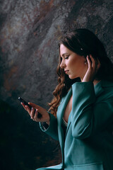 Luxurious girl with beautiful makeup and hairstyle, permanent makeup specialist, holds tools in her hands. Photoshoot in a photo studio in a suit, jeans and a shirt.