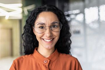 Close up photo portrait of beautiful Latin American woman with curly hair and glasses,...