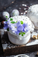 Easter cake with meringue and violets on a dark background