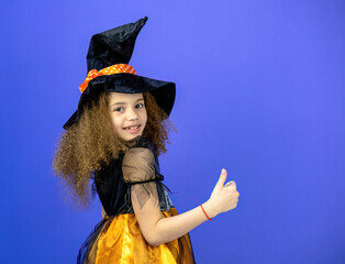 A beautiful and cute girl in a dress on a colorful purple background shows emotions, the concept of the Halloween holiday.