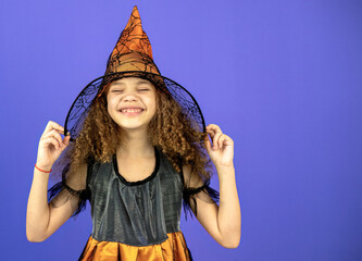 A beautiful and cute girl in a dress on a colorful purple background shows emotions, the concept of the Halloween holiday.