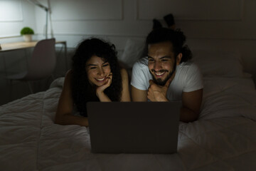 Cheerful couple watching a movie before sleeping
