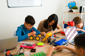 Group of smart teens assembling a robot prototype together