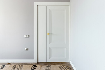 White door consisting of two halves against a gray wall, after installation