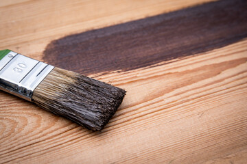 Brush with brown paint on a wooden texture background