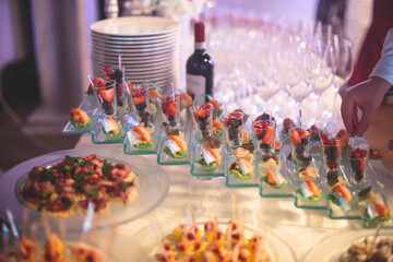 Catering table, beautifully decorated banquet with variety of with different food snacks appetizers on corporate birthday party event or wedding celebration, canape, salad, delicatessen setting