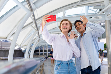 Diversity couple is taking selfie using mobile phone while socializing and enjoying happy lifestyle of living in urban metropolitan downtown for modern universal design city
