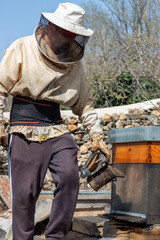 Beekeeping smoker. The beekeeper lighting it with different fuels and applying the smoke in the hives