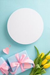 Fototapeta na wymiar Happy mother's day trendy concept. Top view of trendy gift boxes and yellow tulips on pastel blue background with empty circle for text or greeting message