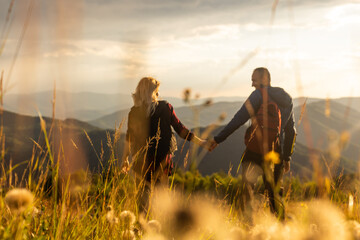 A man and a woman in tourist equipment are standing on a rock and admiring the panoramic view. A couple in love on a rock admires the beautiful views. A couple in love is traveling. A couple on a hike