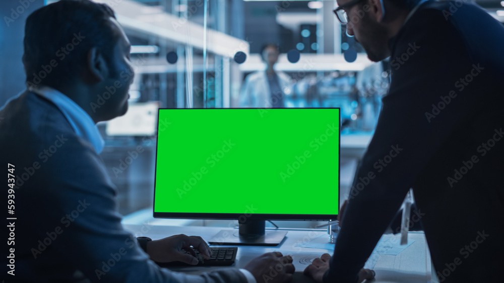 Aufkleber Two Developers Working on Computer with Green Screen Mock Up Display. Scientific Lab, Engineering Research Center with Specialists Working on Turbine Engine Development in the Background.