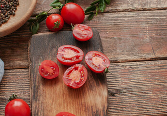 cocktail  tomatoes on a wooden board with various vegetables and garlic and black pepper