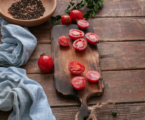 cocktail  tomatoes on a wooden board with various vegetables and garlic and black pepper