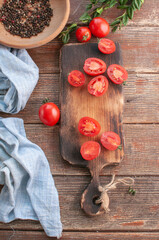 cocktail  tomatoes on a wooden board with various vegetables and garlic and black pepper