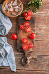 cocktail  tomatoes on a wooden board with various vegetables and garlic and black pepper