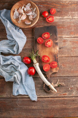 cocktail  tomatoes on a wooden board with various vegetables and garlic and black pepper