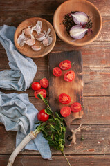 cocktail  tomatoes on a wooden board with various vegetables and garlic and black pepper