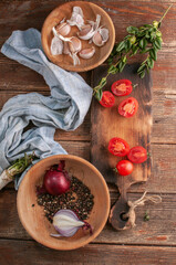 cocktail  tomatoes on a wooden board with various vegetables and garlic and black pepper