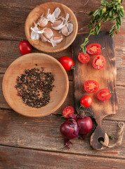 cocktail  tomatoes on a wooden board with various vegetables and garlic and black pepper