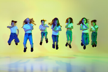 Performance. Little girls, children in casual sporty style clothes dancing, jumping against green...
