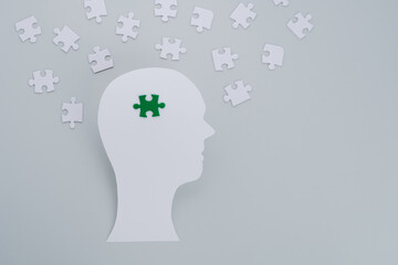 Concept of green business devotion, sustainability and negative impacts on the environment showing by paper-cut of human head with choice green puzzle on a gray background. flat lay