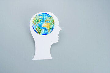 Paper cut of human head with painting planet Earth as brain on a gray background. Ecological and environmental protection concept 