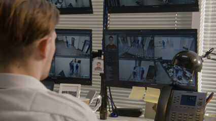 Security officer monitors office CCTV cameras on computers, uses walkie talkie. High tech software showing footage of surveillance cameras with facial recognition on screens. Concept of social safety.