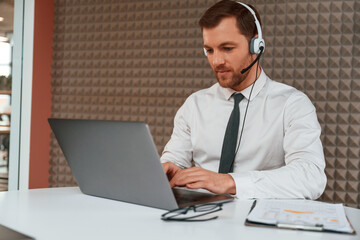 Using laptop. Handsome man in formal clothes is in the office