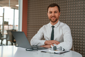 Fototapeta premium Handsome man in formal clothes is working by laptop in the office