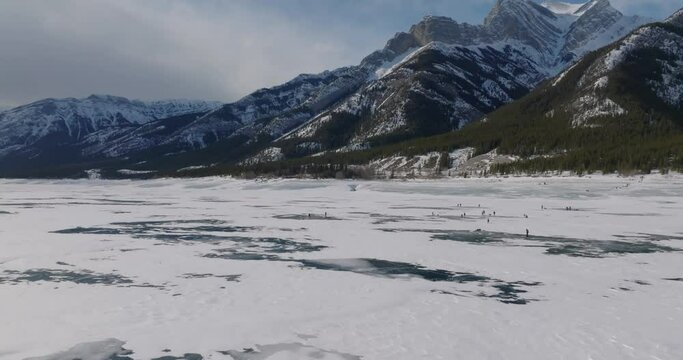 people walking on frozen lake abraham with canadian rocky mountains during winter