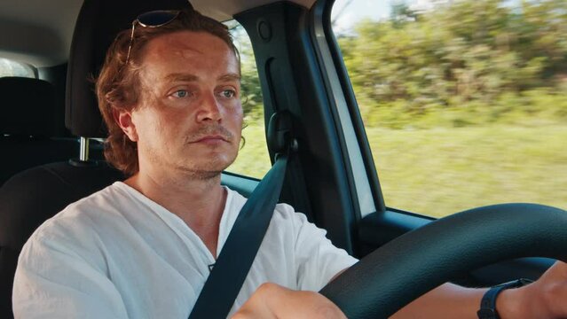 Tired sleepy young man drives the car on a highway and slowly closes his eyes. Man closes his eyes while driving a car and loses concentration