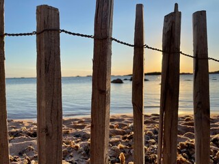 Obraz premium Plan rapproché d'une barrière en bois sur la plage de la Tonnara, avec le sable, la mer et le coucher du soleil à l'arrière-plan