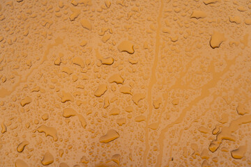 Gouttes posées sur une carrosserie de couleur orange métallisé.