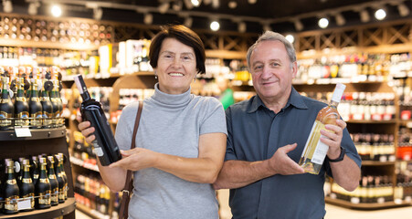 Elderly man and elderly woman choose bottle of alcohol