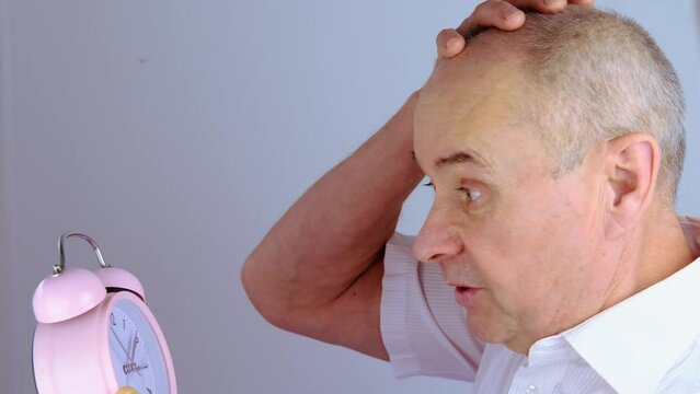 close-up mature man, senior 60 years old holds alarm clock in hand, concept missing time, oversleeping important meeting, life deadline, active SeniorLife, old age crisis, decrease in overall activity
