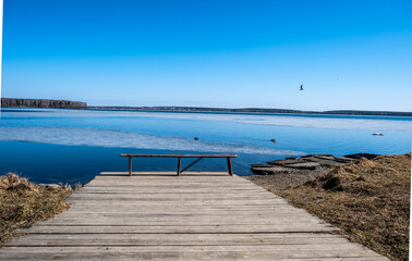 A bench on a wooden pier on the shore of the lake.