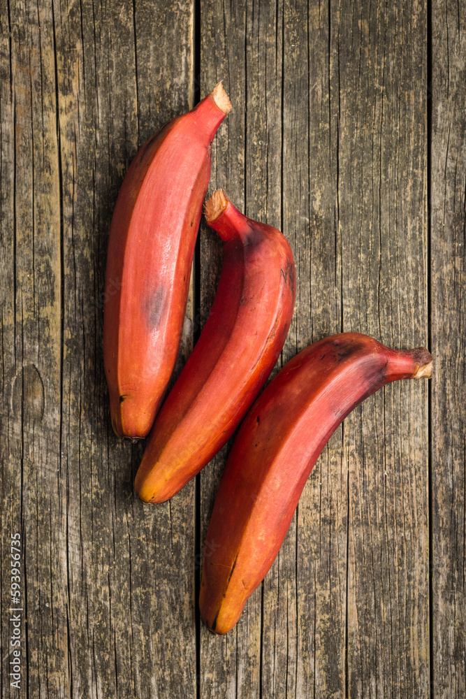 Sticker Tasty red bananas on wooden table. Top view.