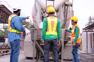 Workers and cement mixer at construction site.