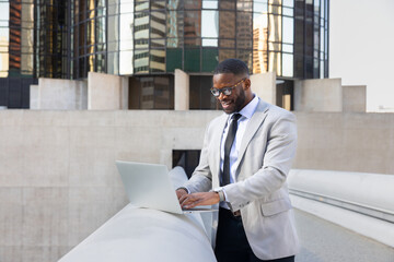 Fototapeta premium Successful Black Manager Using Computer In Front OF Modern Office Buildings