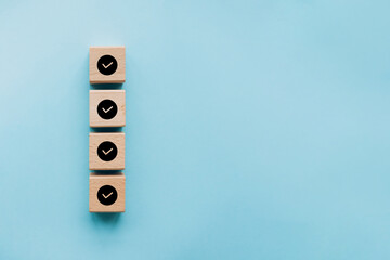 Checklist concept, Check mark on wooden blocks, blue background with copy space