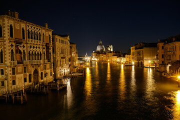 Fototapeta premium Venice, Italy: Night view of Venice Grand Canal with boats and Santa Maria della Salute church on sunset from Ponte dell'Accademia bridge. Venice, Italy