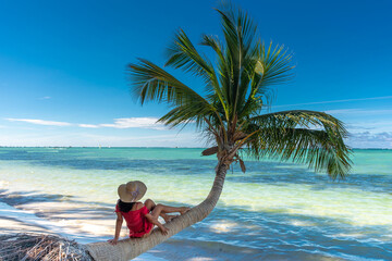 Fototapeta na wymiar Dominican Republic of Punta Cana, a girl in a hat on the ocean with turquoise water and palm trees.
